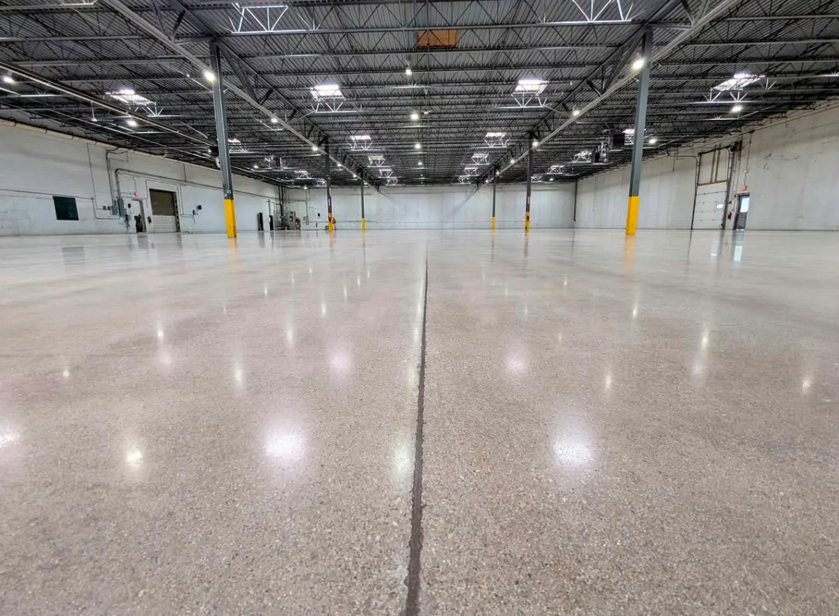 Polished concrete warehouse floor with a saw-cut joint running into the distance