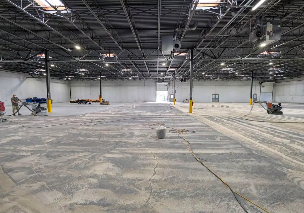 Warehouse slab partway through grinding, dust and cracks still showing